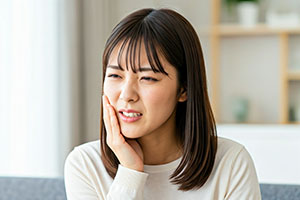 歯が痛くて頬をおさえる女性