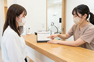 受付で次回予約を確認する女性